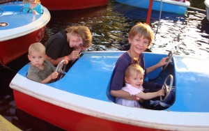 big kids with little kids in amusement park kiddie ride boat