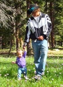 big teen and toddler walking holding hands in field of flowers