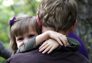 little sister with arms around neck of big brother