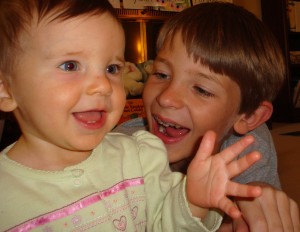big bro smiling at baby sister smiling